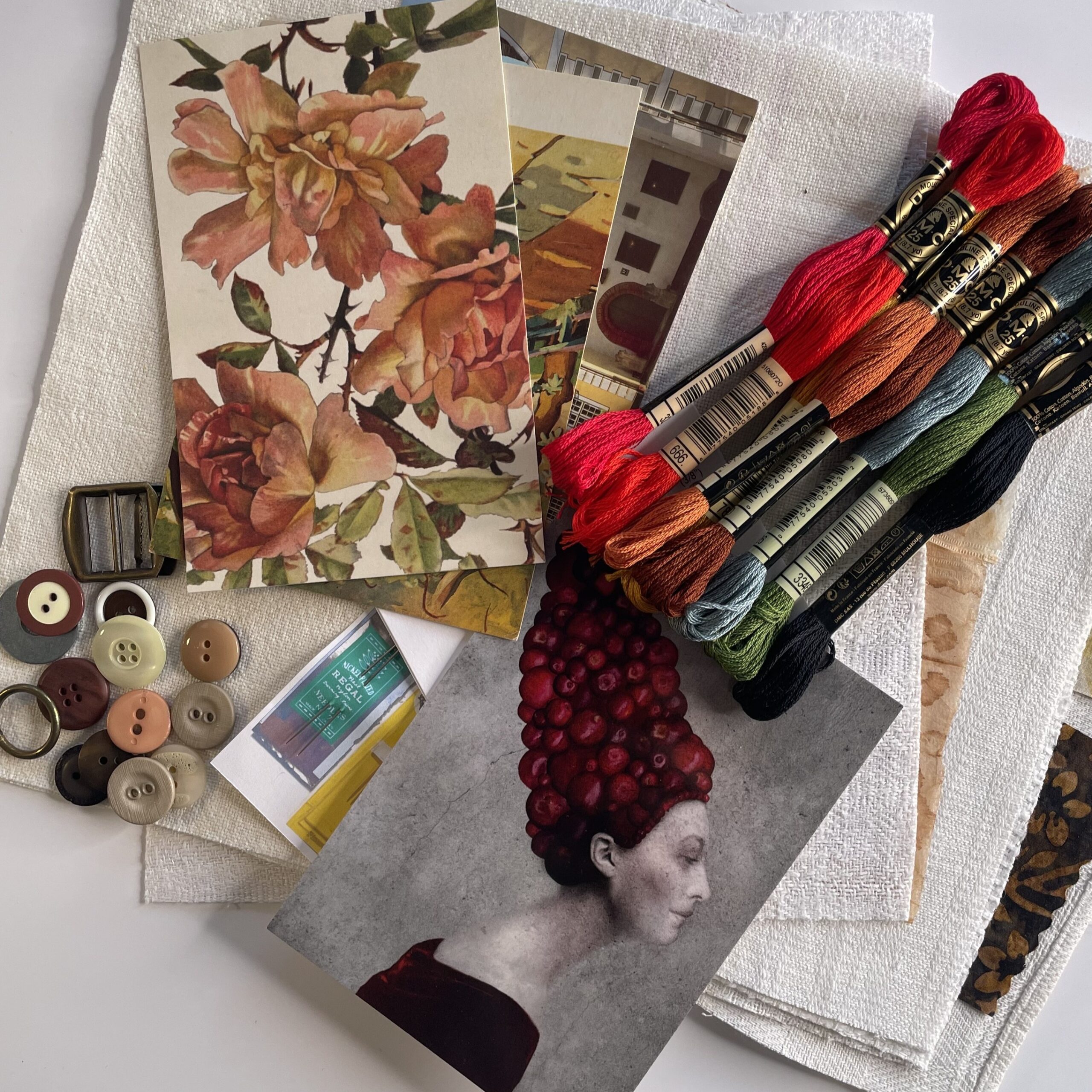 Slow stitchingissä käytettäviä materiaaleja: kankaita, kirjontalankoja, neuloja, nappeja. postikortteja.