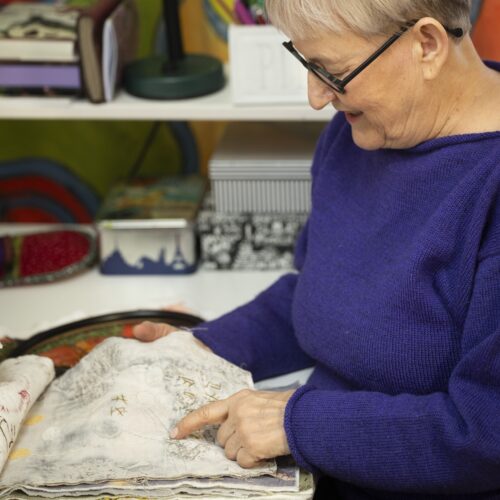 iinasmoko tarkastelee ommeltua kuvaa. Kankaiden väliin on ommeltu sakset.