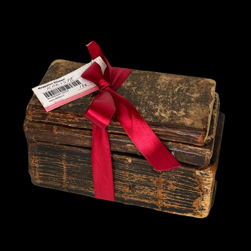 Kolme vanhaa kirjaa sidottuna punaisella satiininauhalla nipuksi.